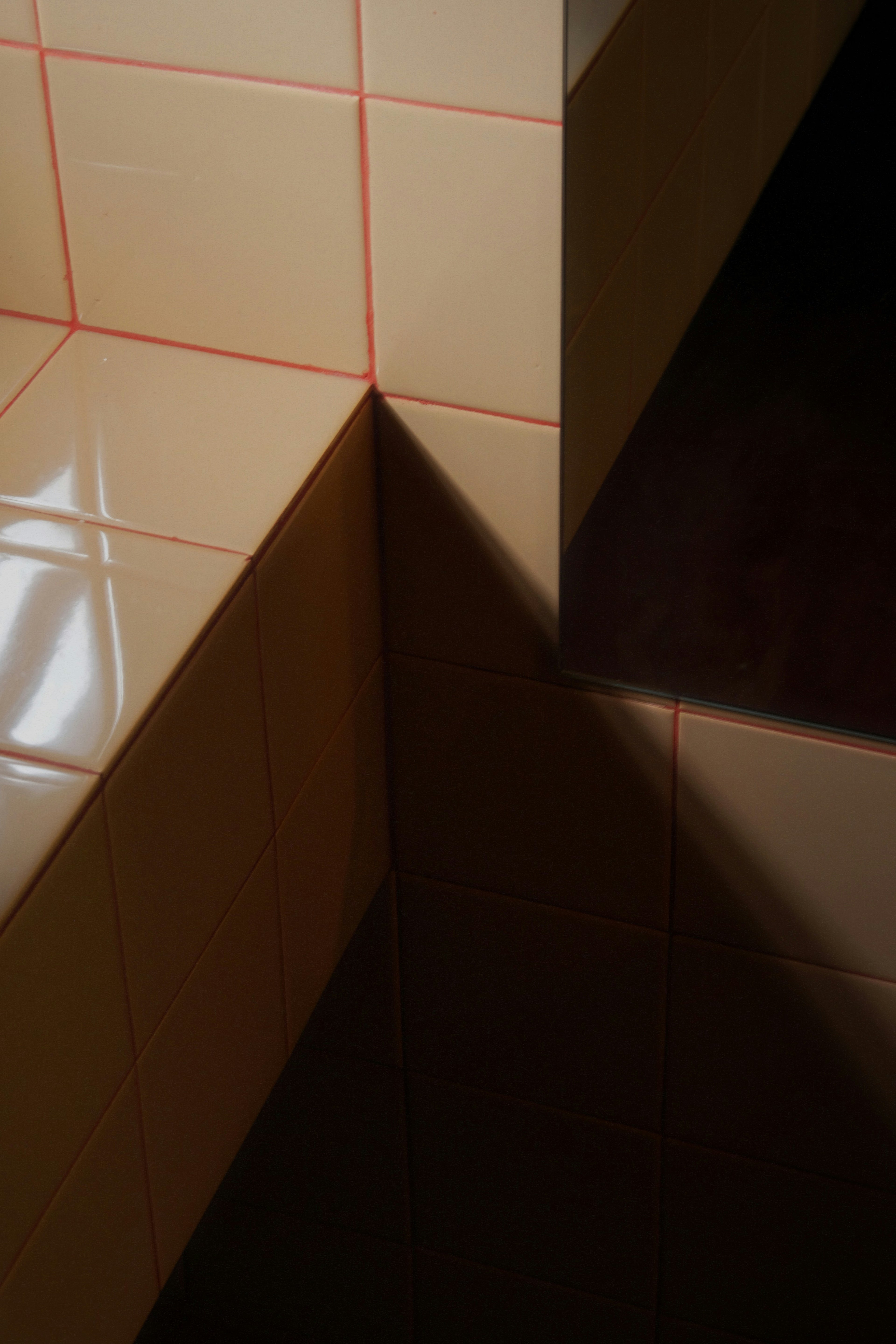 Corner of a tiled wall with red grout lines
