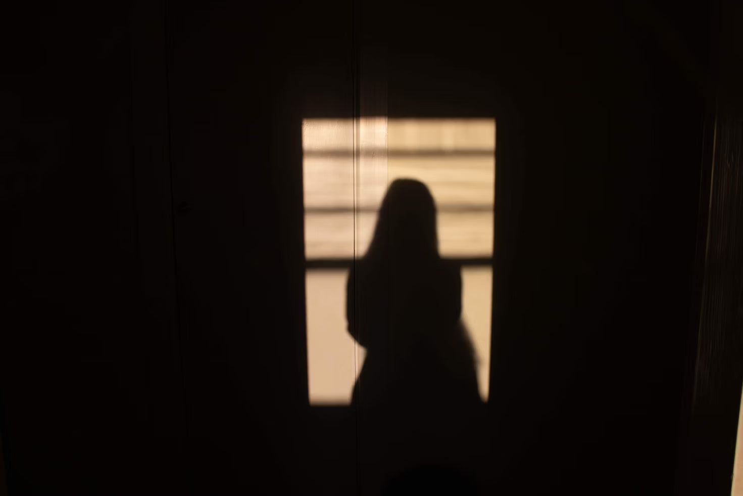 Silhouette of a person against a window with light filtering through