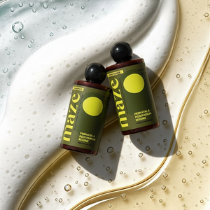 Two bottles of 'maze' product on a textured surface with water droplets.